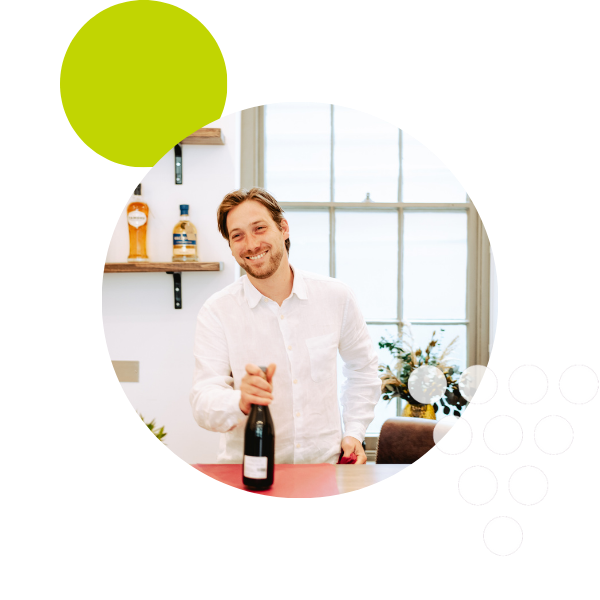 Julian holding a bottle of red wine on the counter at Blenheim Vintners setting with a green circle overlay