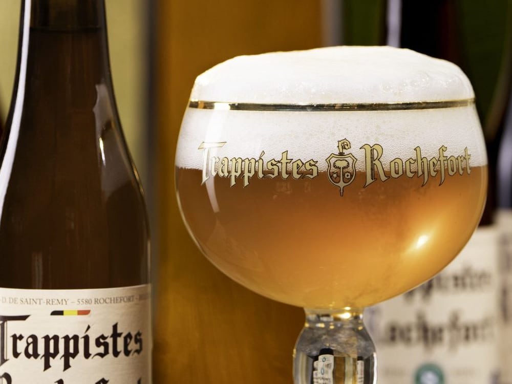 Trappistes Rochefort beer bottle and glass with brand name on a blurred background